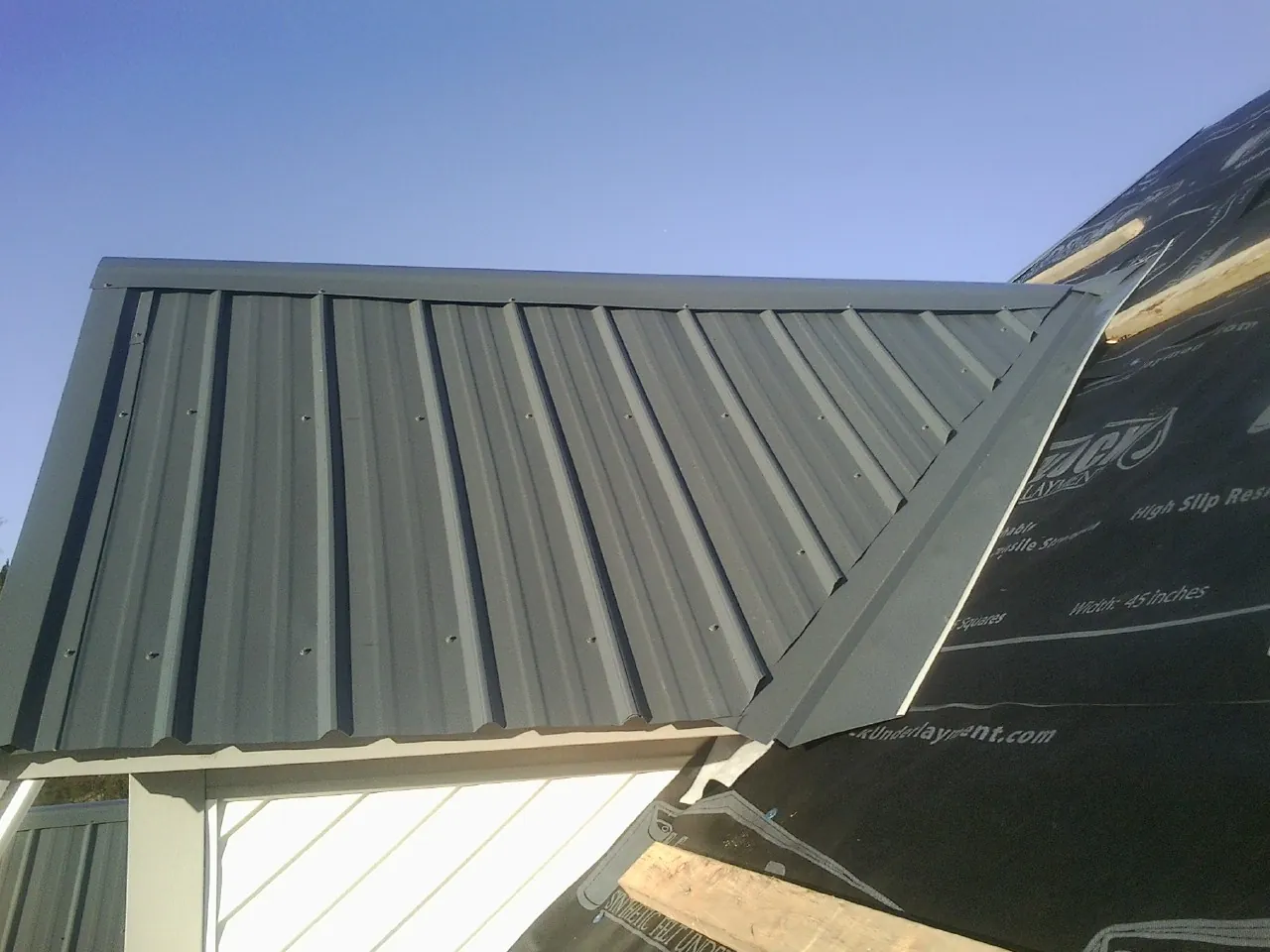 Gray metal roof panels going on over a garage gable in Gordon