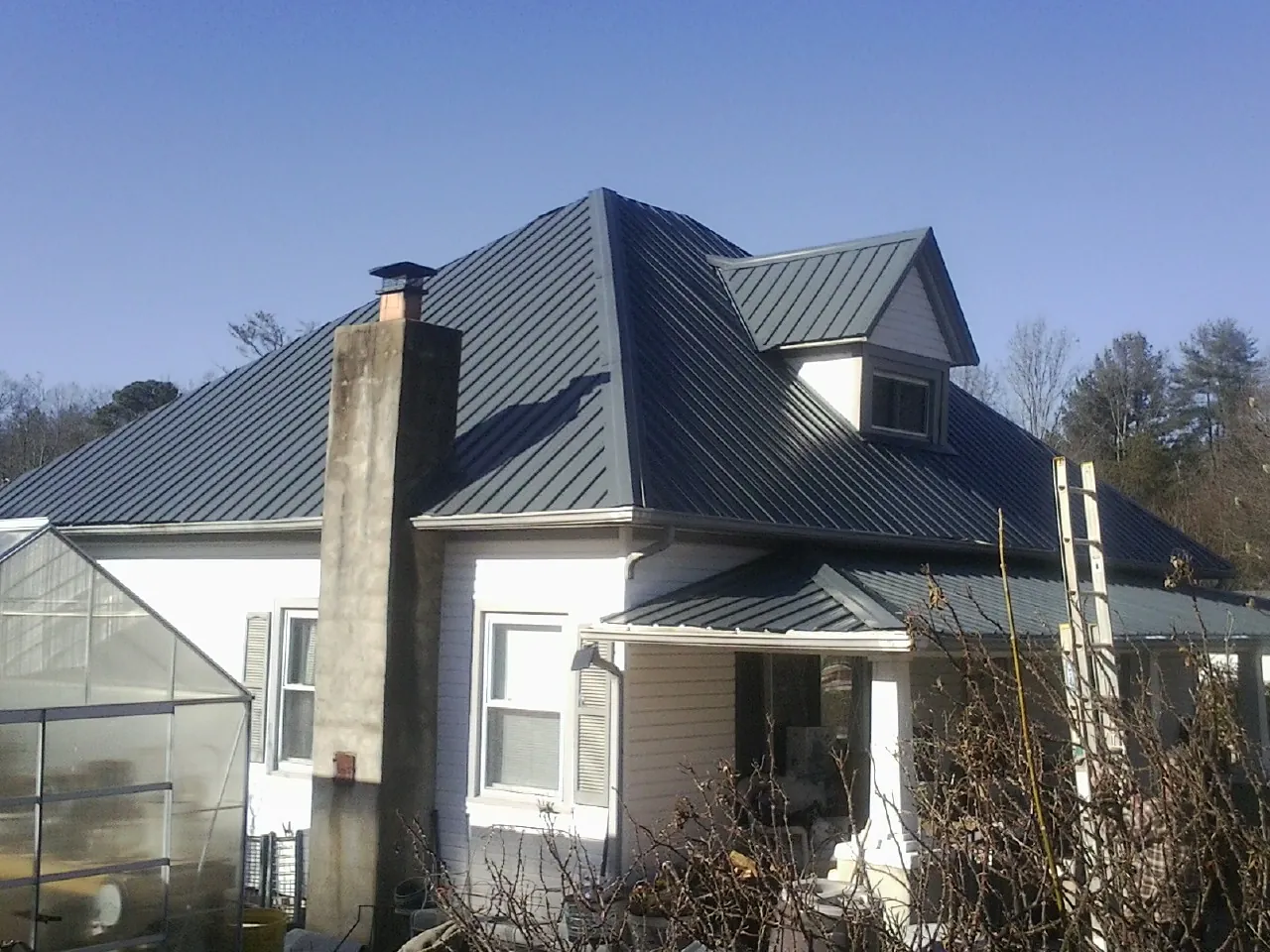 Dark blue standing seam metal roof on a white farmhouse with dormer — Slate & Tile Roof Repair by Roofing Brothers in Gordon