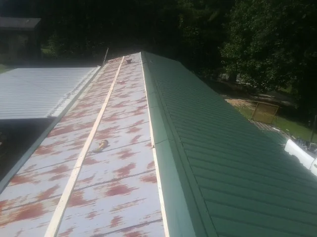Old rusted panels beside newly installed green metal roofing — Wind Damage Roof Repair by Roofing Brothers in Gordon