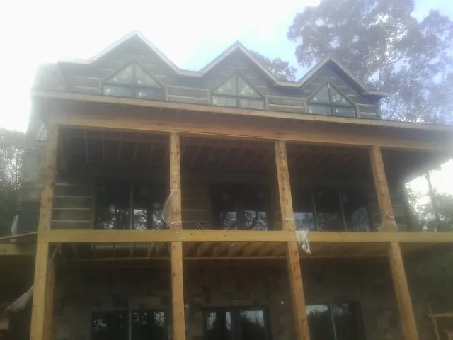 Dormers and porch framing on a large log home under construction — Roof Coating work by our crew in Gordon