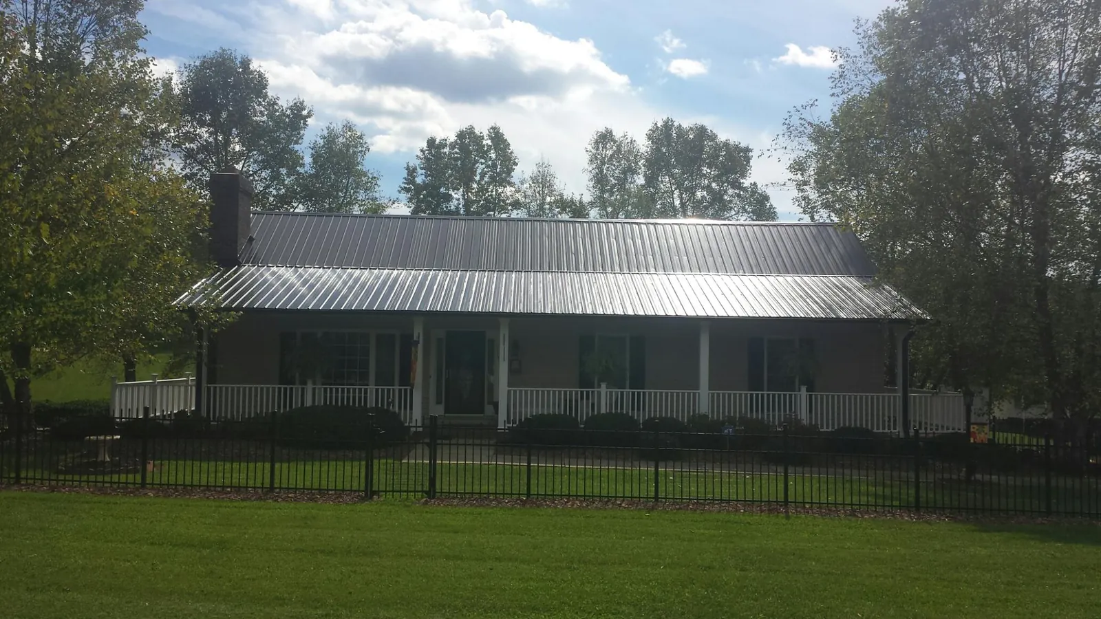 Gray metal roof on a brick ranch with a full width front porch — Gutter Guard Installation work by our crew in Gordon
