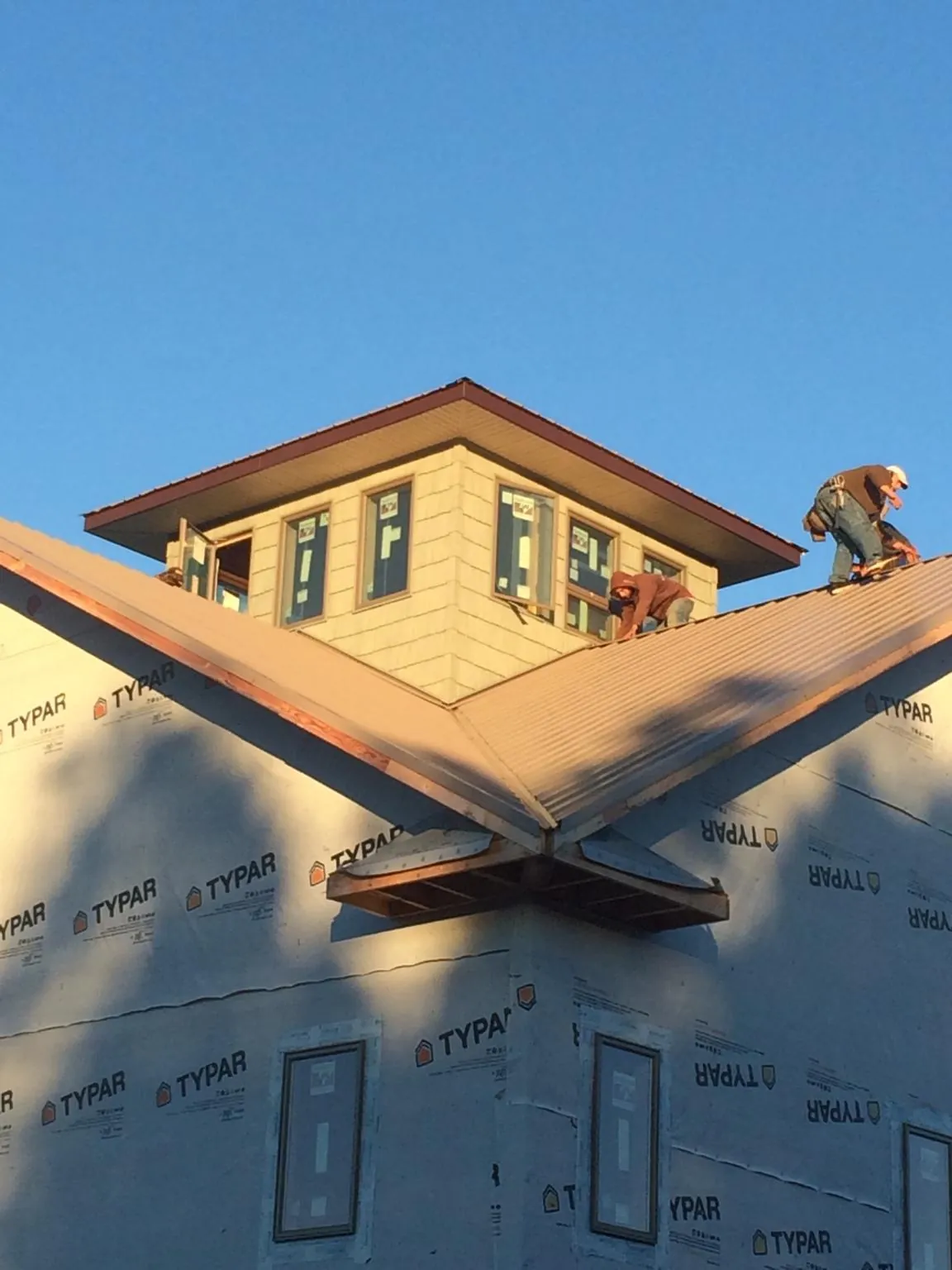 Roofers working around a rooftop cupola on a new metal roof at sunset — Roof Waterproofing in Gordon by Roofing Brothers
